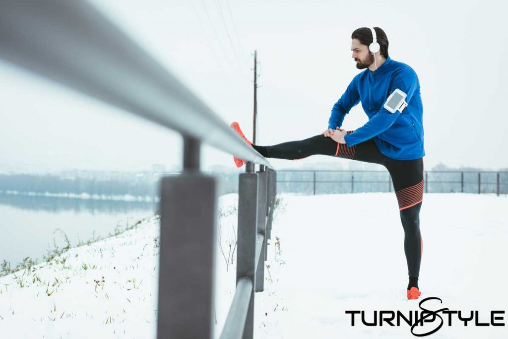 Man wearing HEADPHONES stretching in the cold