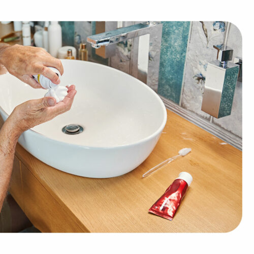 Man in wheelchair dispensing shave foam into his hands over the sink