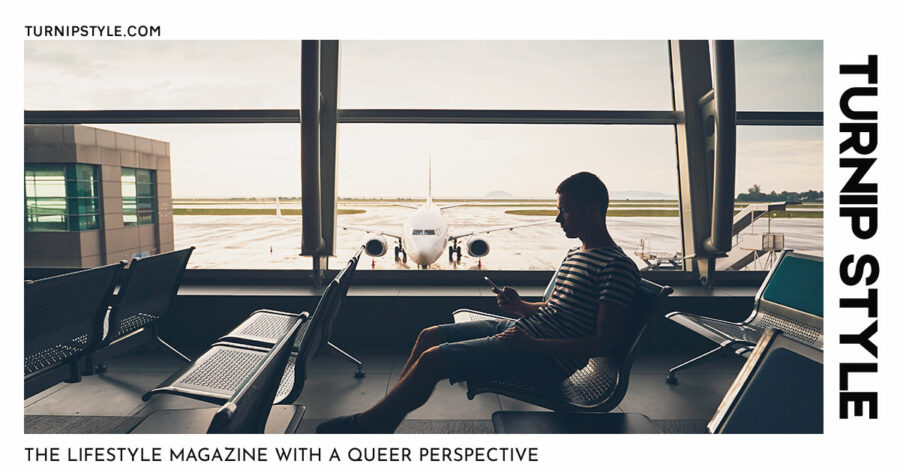 Man in airport boarding lounging, waiting for a flight and looking at his mobile device.