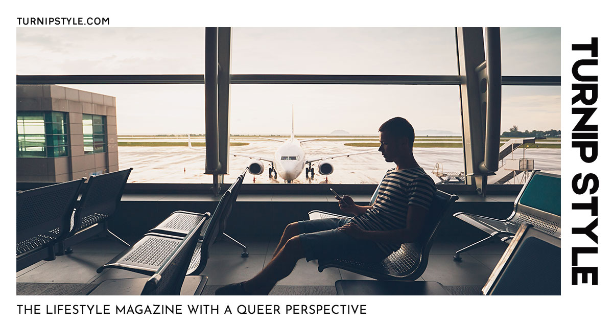 Man in airport boarding lounging, waiting for a flight and looking at his mobile device.